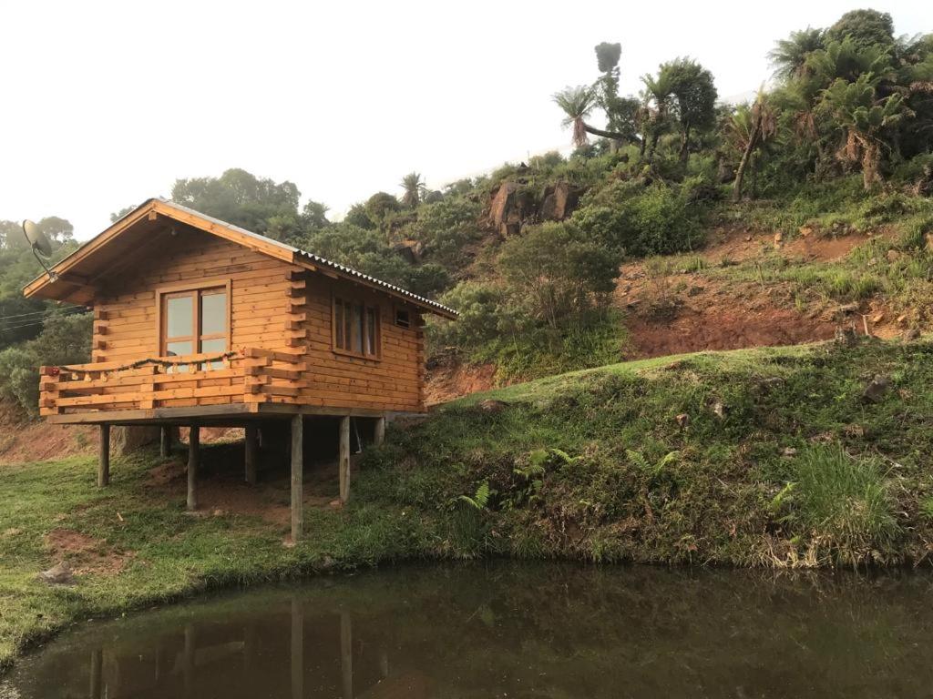 eine Holzhütte auf einem Hügel neben einem Wasserkörper in der Unterkunft Cabana da Colina 2 in Bom Jardim da Serra