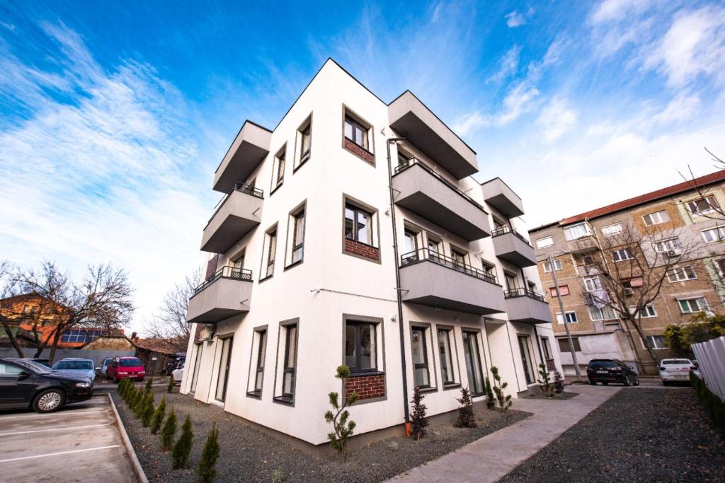 a white building with cars parked in front of it at THE NOOK APARTHOTEL in Timişoara