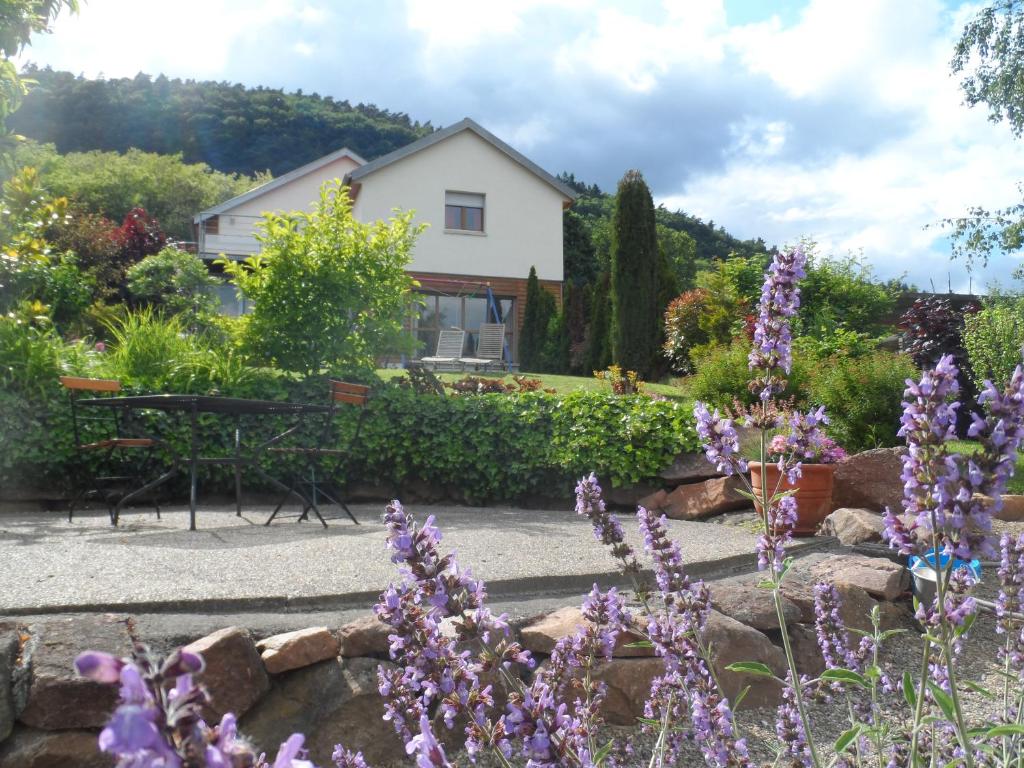 un jardín con flores púrpuras frente a una casa en Chambres d'Hôtes Rachelle Schneider, en Husseren-les-Châteaux