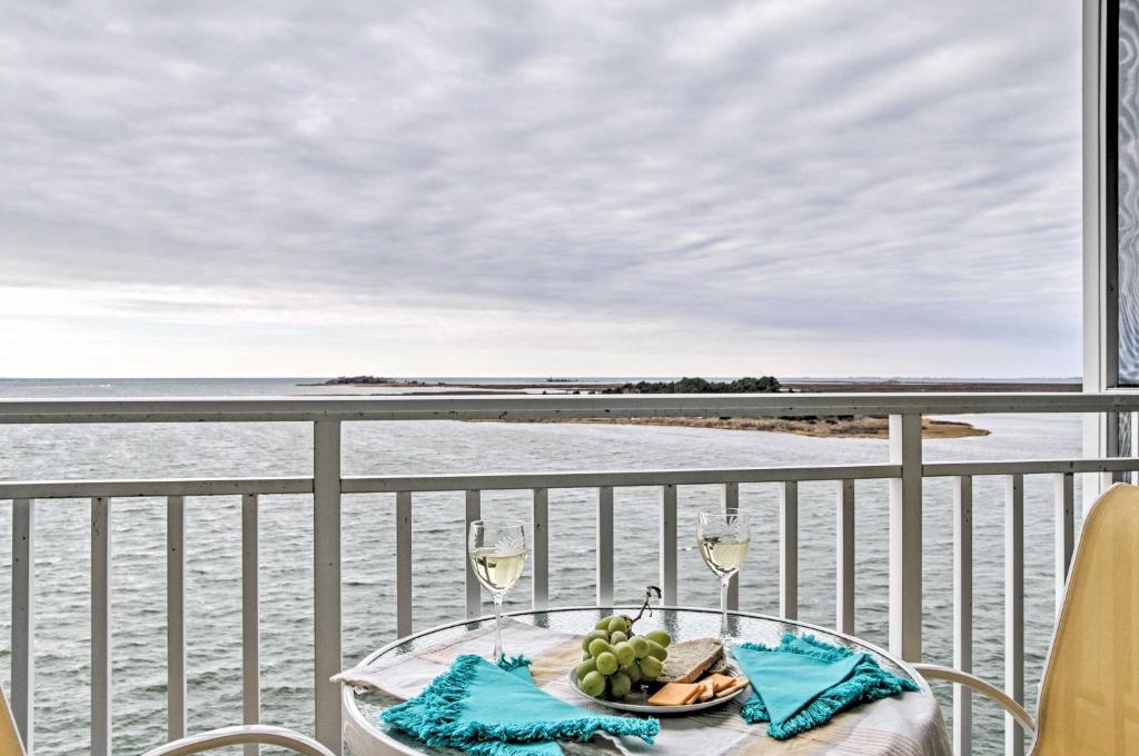 a table with wine glasses and a plate of food on a balcony at Beautiful Waterfront Condo with Community Pool! in Crisfield