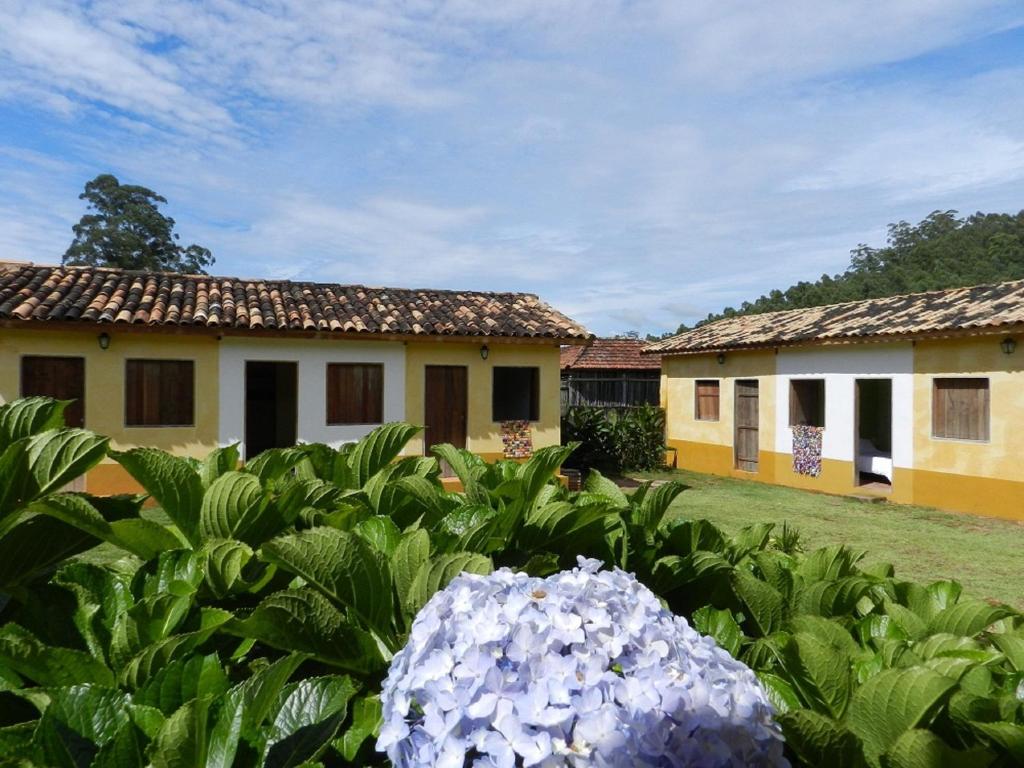 a house with a bunch of flowers in the yard at Pousada Fazenda São Luiz in São Luiz do Paraitinga