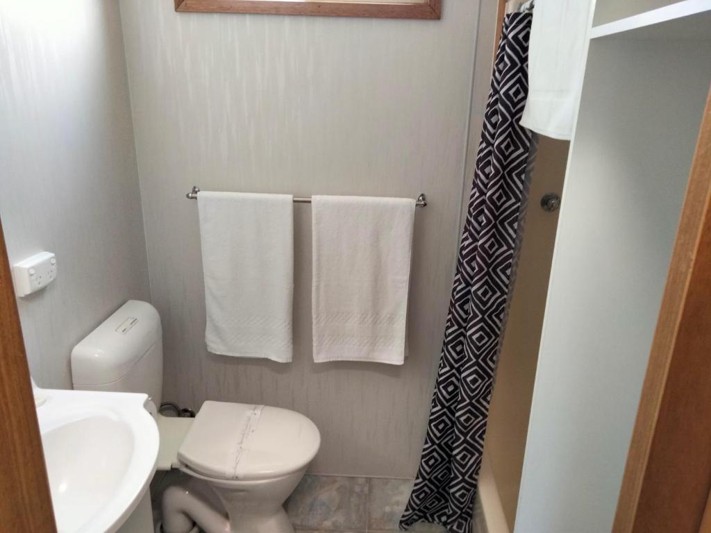 a bathroom with a toilet and a sink and towels at Beach Haven Caravan Park in San Remo