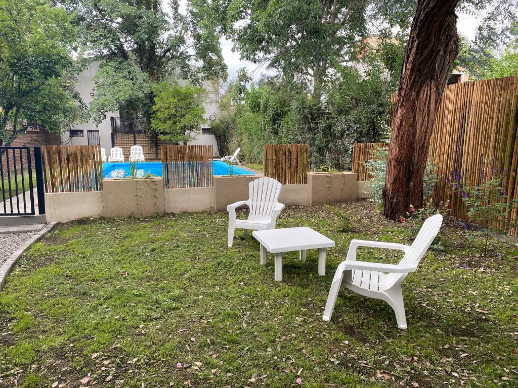 duas cadeiras brancas e uma mesa num quintal em La Escondida Salta 1 em Salta