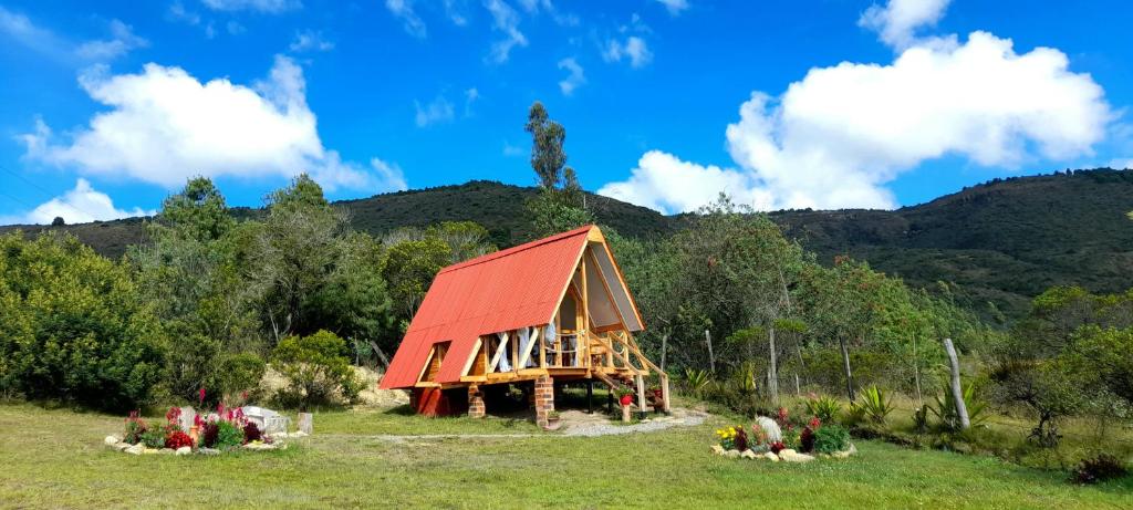 a small house with a red roof in a field at Dante Glamping in Guatavita
