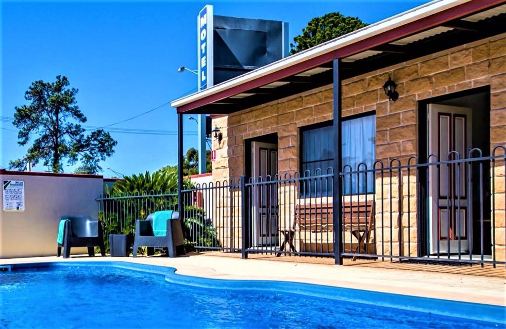 une maison avec une piscine à côté d'un bâtiment dans l'établissement Ascot Lodge Motor Inn, à Kingaroy