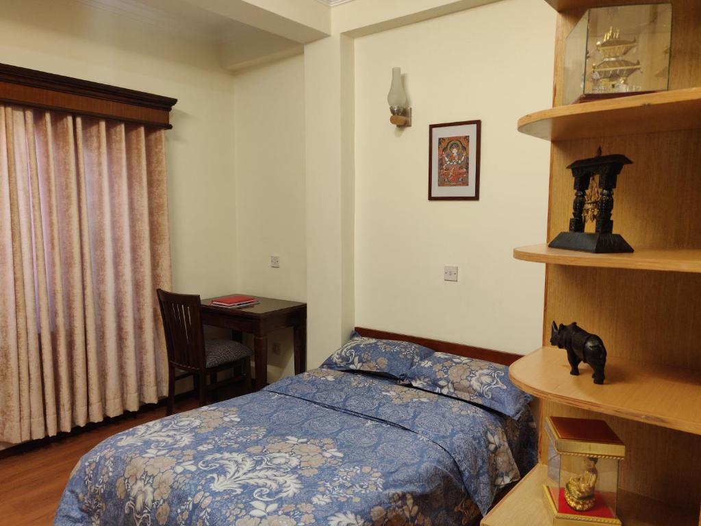 a bedroom with a bed and a desk with a chair at Peace Home Apartment Swayambhu in Kathmandu