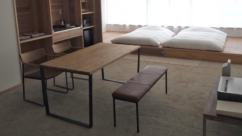 uma mesa e cadeiras num quarto com uma cama em HUB INN em Onomichi