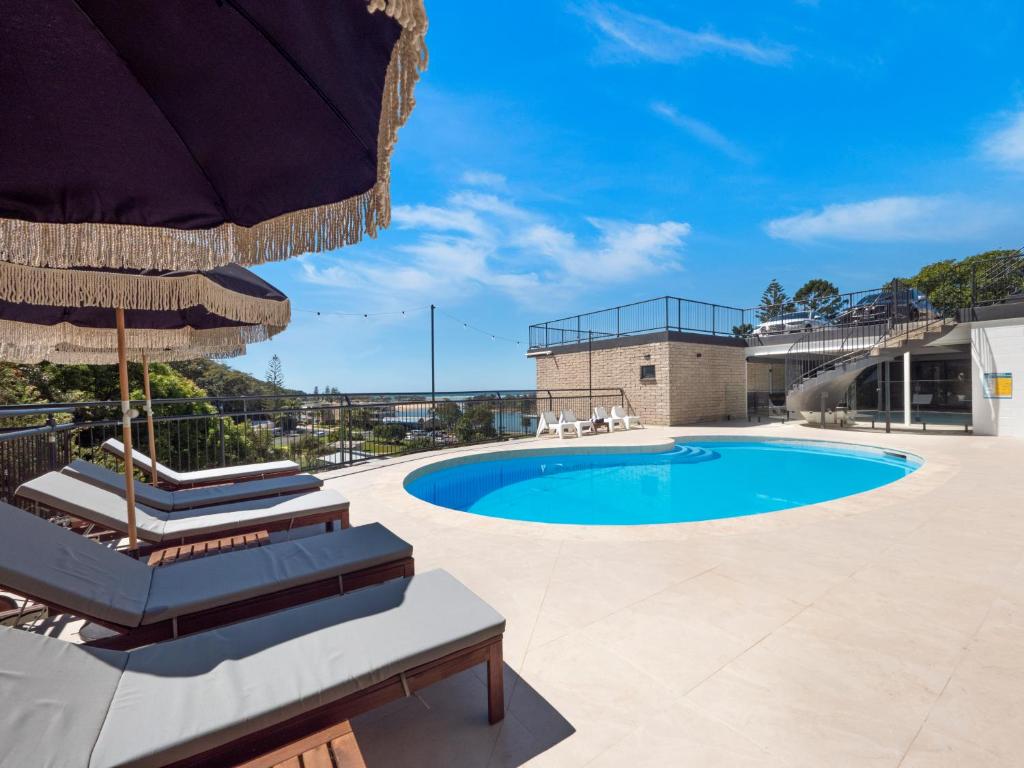 a swimming pool with two lounge chairs and an umbrella at The Beach Rooms in Nambucca Heads