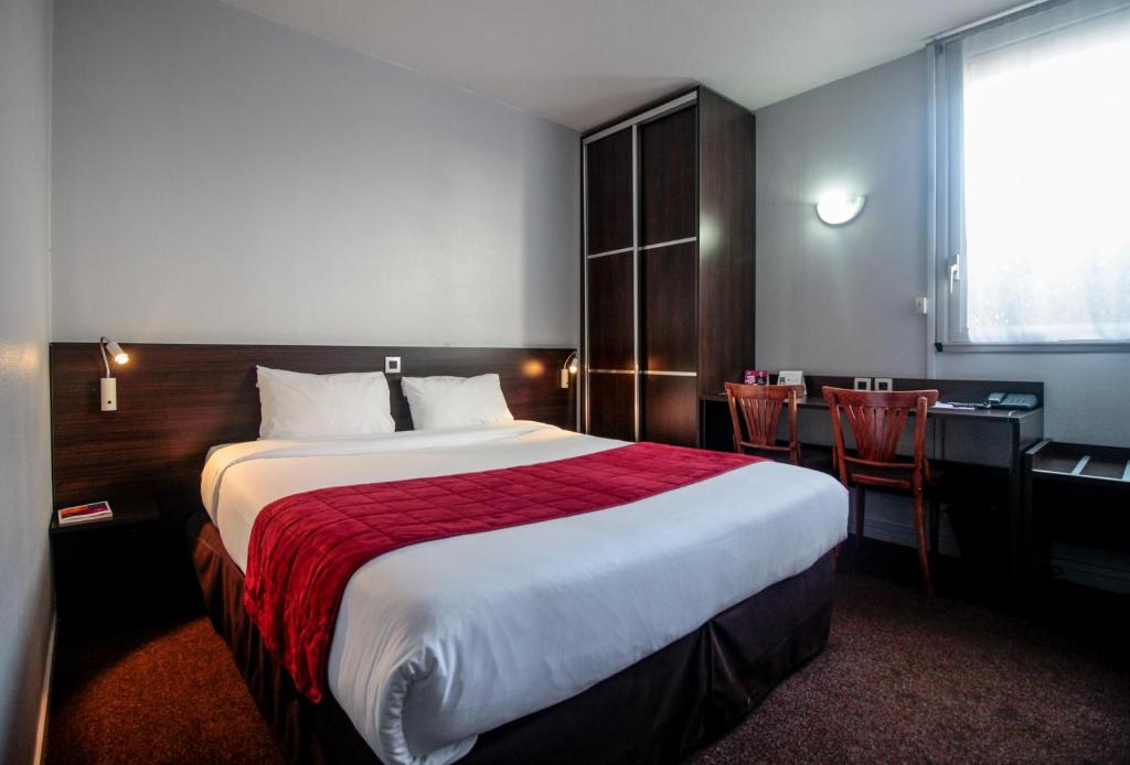 una camera d'albergo con un grande letto e una scrivania di The Originals City, Hôtel du Phare, Bordeaux Mérignac (Inter-Hotel) a Mérignac