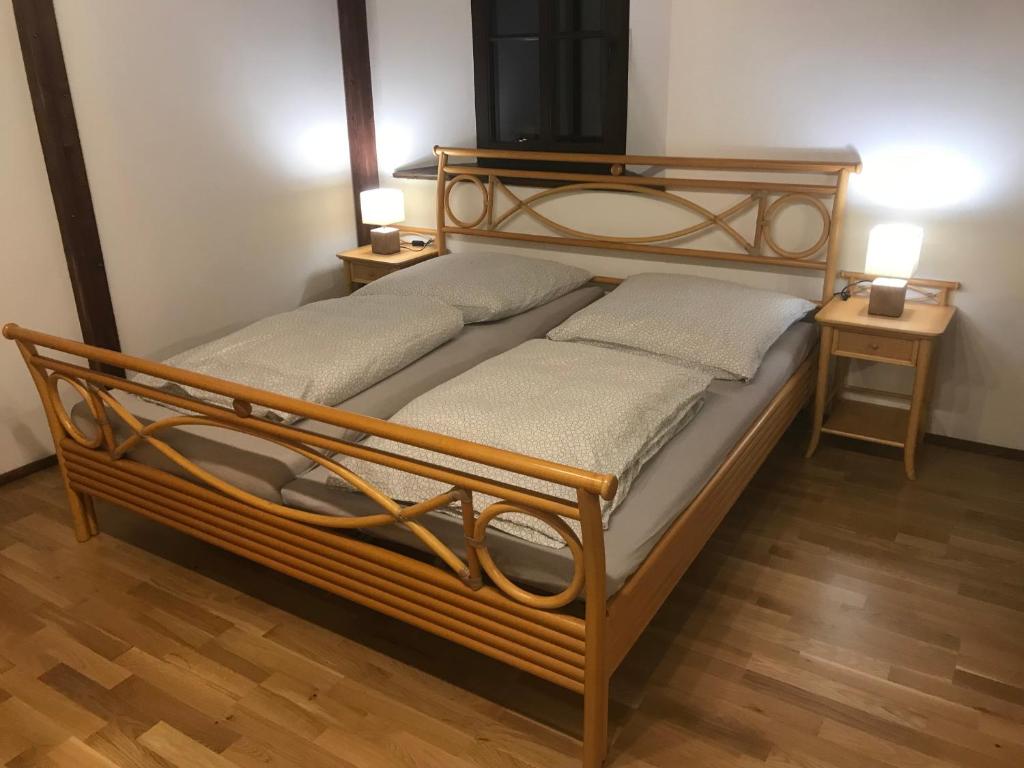 a wooden bed in a room with two tables at Ferienwohnung PENZLIN im Rittergut Leppersdorf bei Dresden in Wachau