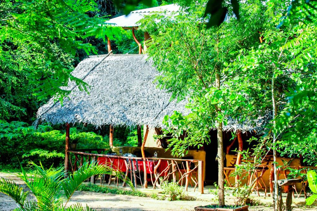 a hut with a thatched roof in a forest at Relax Nature Villa in Sigiriya