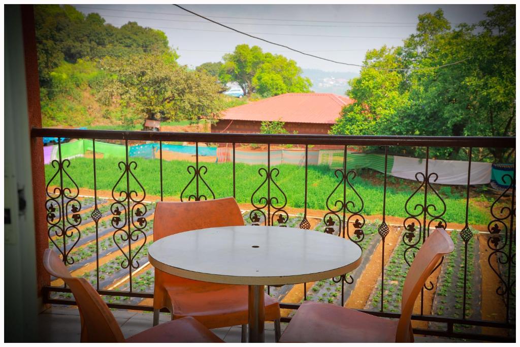 a balcony with a table and chairs and a view of a yard at THE CROFT HOUSE MAHABALESHWAR in Mahabaleshwar