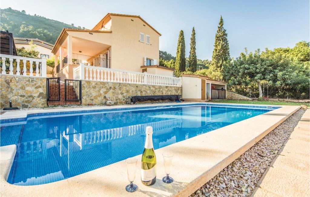 a swimming pool with a bottle of wine in front of a house at Gorgeous Home In Castellon De La Plana With Outdoor Swimming Pool in Castellón de la Plana