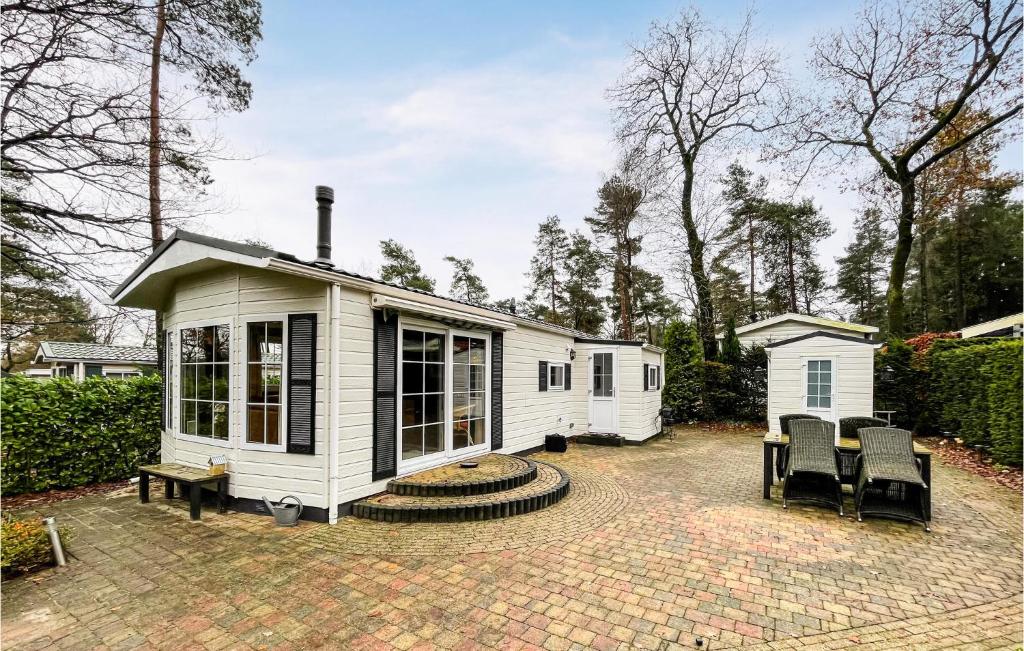 una pequeña casa blanca en un patio de ladrillo en Amazing stacaravan In Beekbergen With Kitchen, en Beekbergen