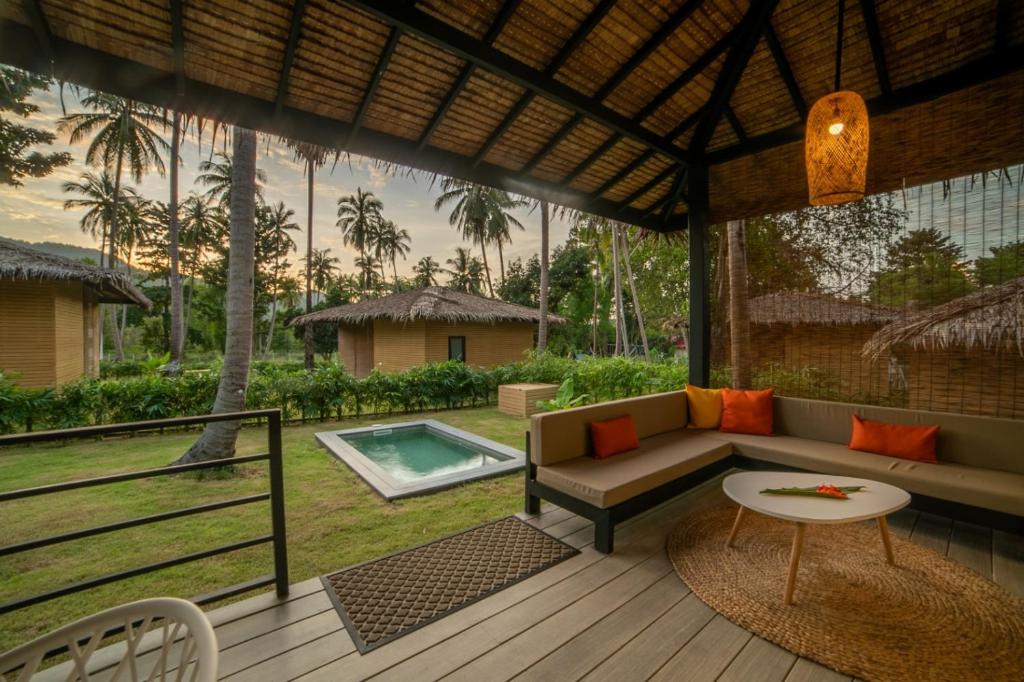 a patio with a couch and a table and a pool at Suan Residence - Exotic and Contemporary Bungalows with Private Pool in Chaloklum