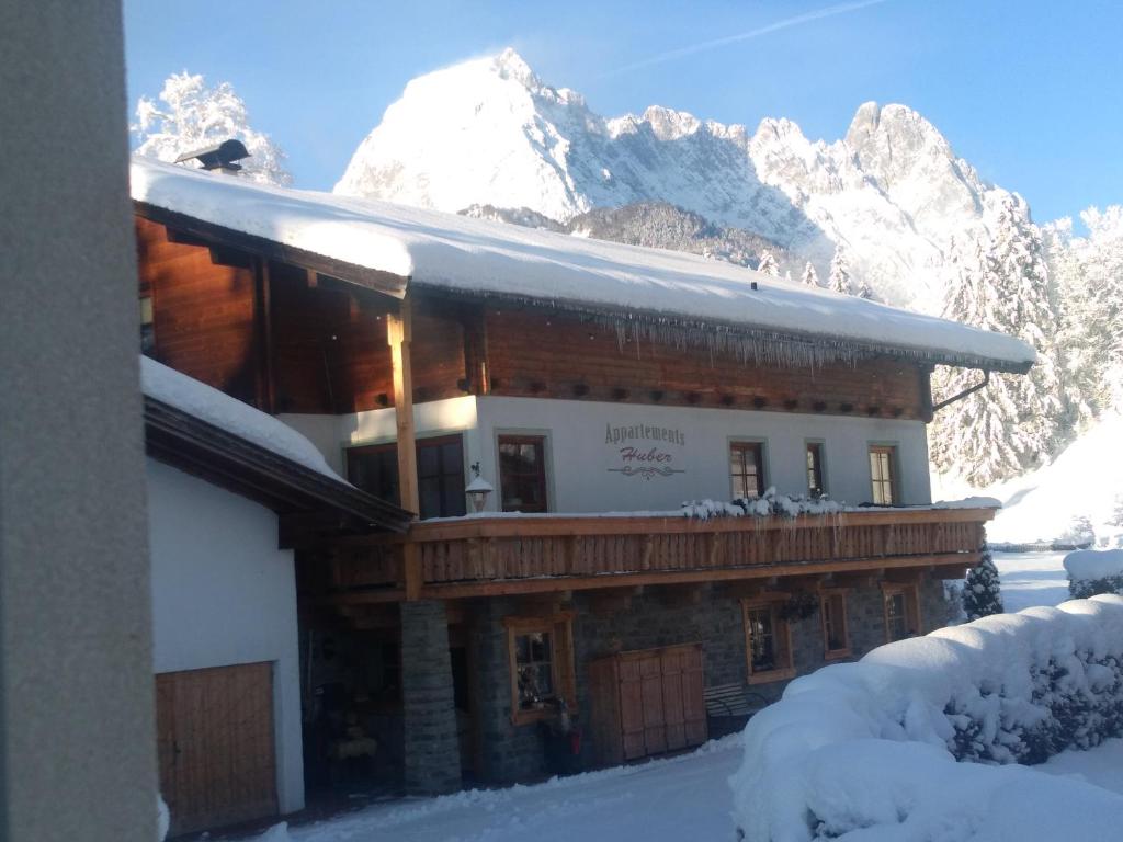 un edificio en la nieve con montañas en el fondo en Landhaus Huber en Kirchdorf in Tirol