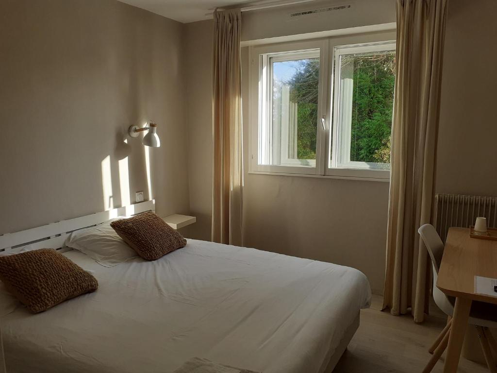 a bedroom with a white bed and a window at Fuzei Hôtel Lorient-Lanester in Lanester