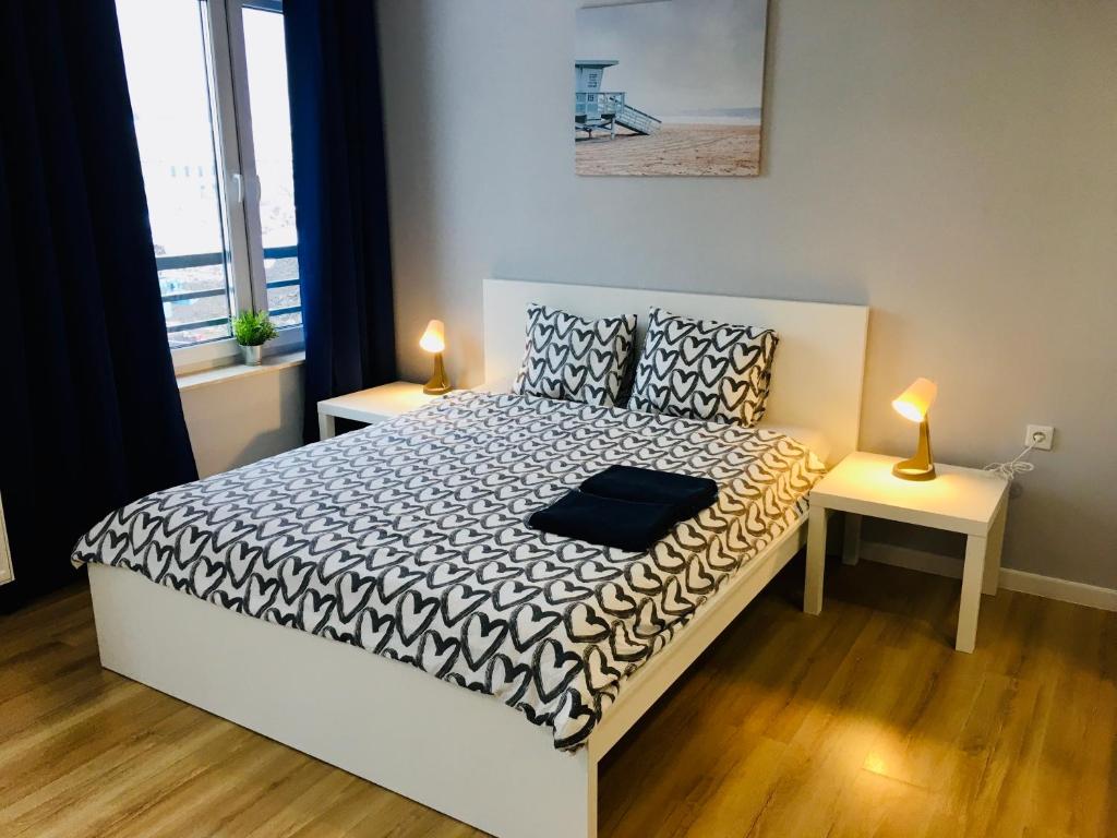 カトヴィツェにあるHoldek Apartamenty Ceglanaのベッドルーム1室(ベッド1台、テーブルにランプ2つ付)