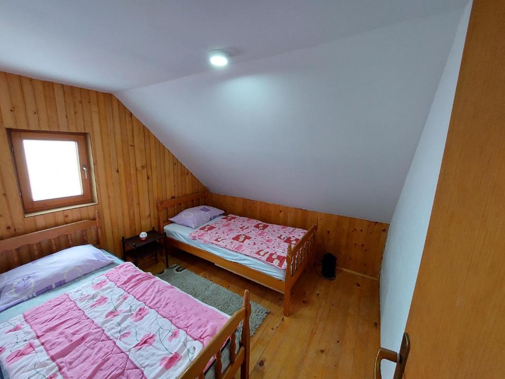 an attic room with two beds and a window at Vikendica Pinus Blidinje in Blidinje