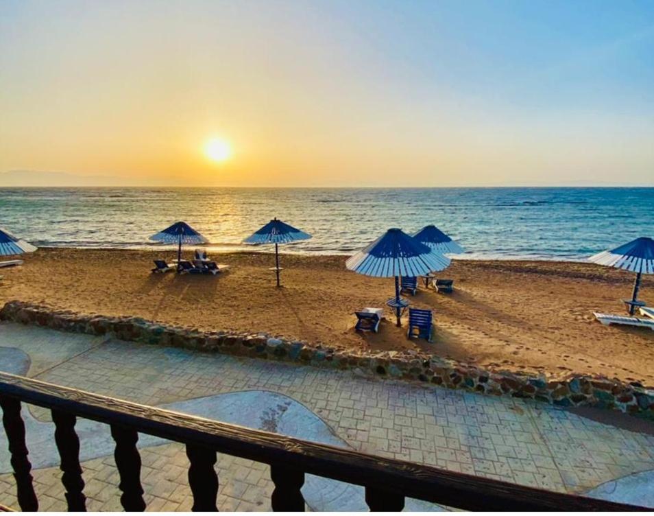 una playa con sombrillas y sillas y el océano en Lagona Dahab Hotel en Dahab