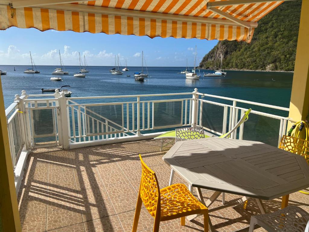 a balcony with a table and chairs and boats in the water at Ti Cabanon. Appartement vue mer à Deshaies. in Deshaies