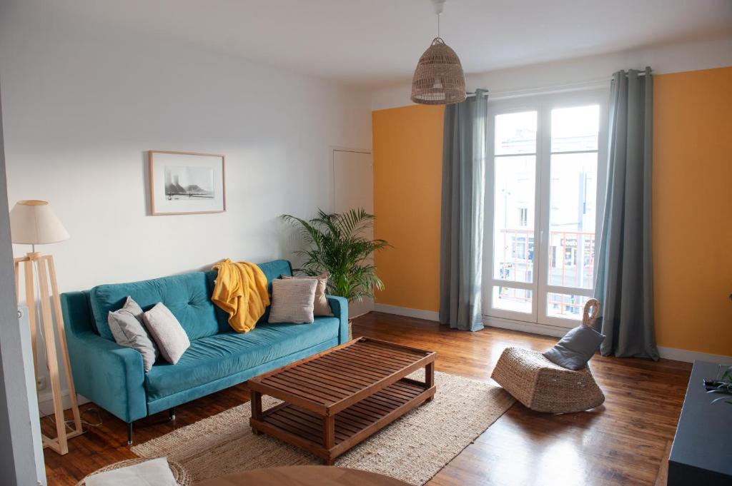 un soggiorno con divano blu e tavolo di Appartement spacieux avec balcon et parking a Brest