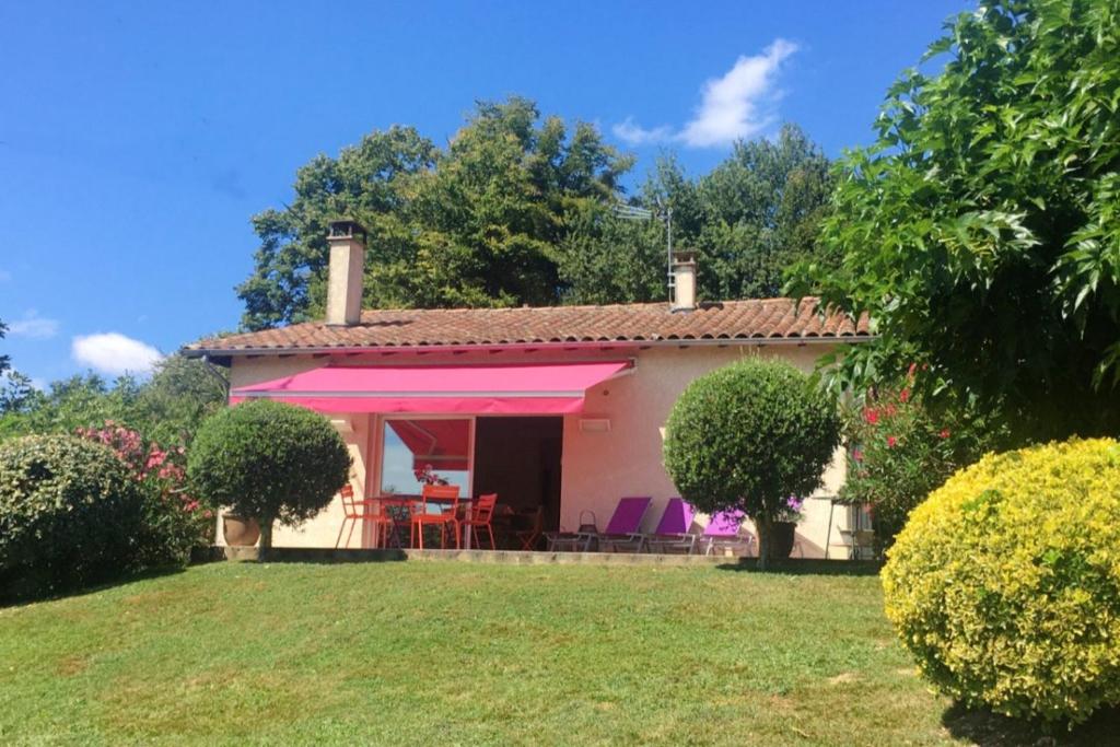 ein kleines weißes Haus mit rosa Markise in der Unterkunft Maison de 2 chambres avec terrasse amenagee et wifi a Monlaur Bernet in Monlaur-Bernet
