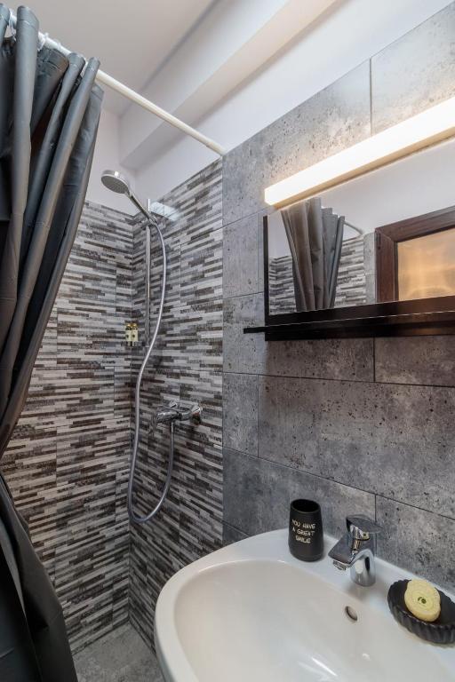un bagno con doccia e lavandino bianco di Pensiunea Doro a Caciulata