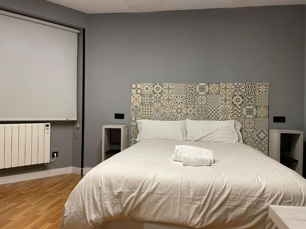 1 dormitorio con 1 cama blanca grande y pared en Belmonte Rooms, en Gijón