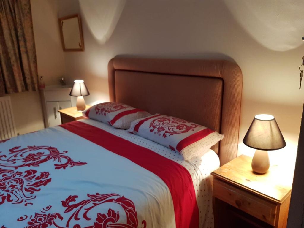 um quarto com uma cama com lençóis e candeeiros vermelhos e brancos em Guest House Ellipse - Finchley em Finchley