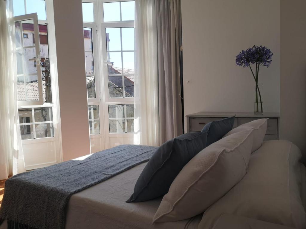 1 dormitorio con cama con almohadas y ventana en Apartamento Bohemia, en Villanueva de Arosa