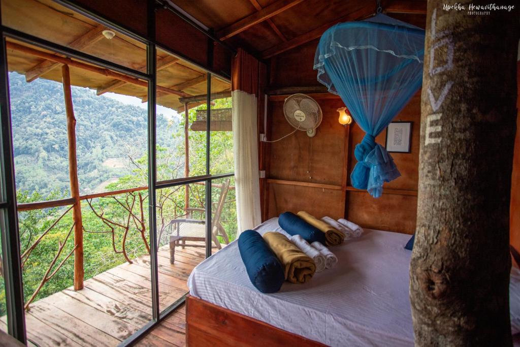 een slaapkamer in een boomhut met een raam bij Tree Houses by Jungle River in Ginigathena