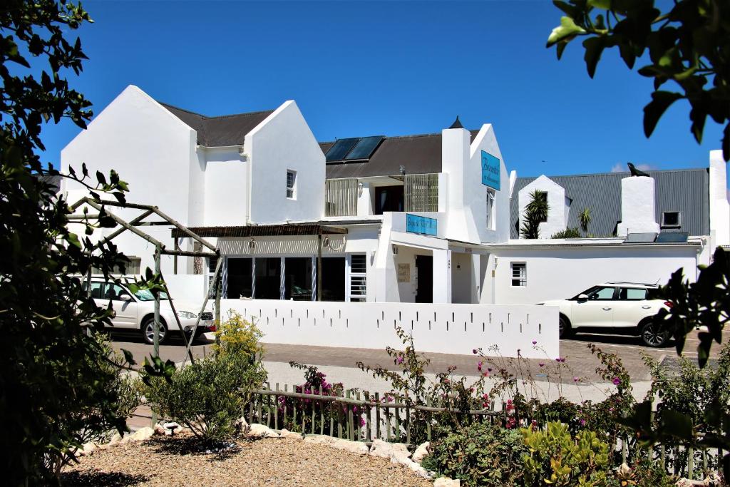 Una casa blanca con autos estacionados frente a ella. en Baywatch Guest House, en Paternoster