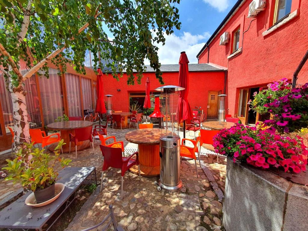 un patio con mesas y sillas y un edificio rojo en CicloLodge, en Lozoya