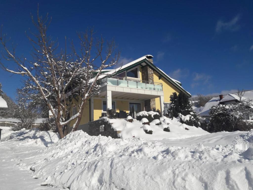 una casa con un montón de nieve delante de ella en Ferienwohnung Kathrin, en Mariahof
