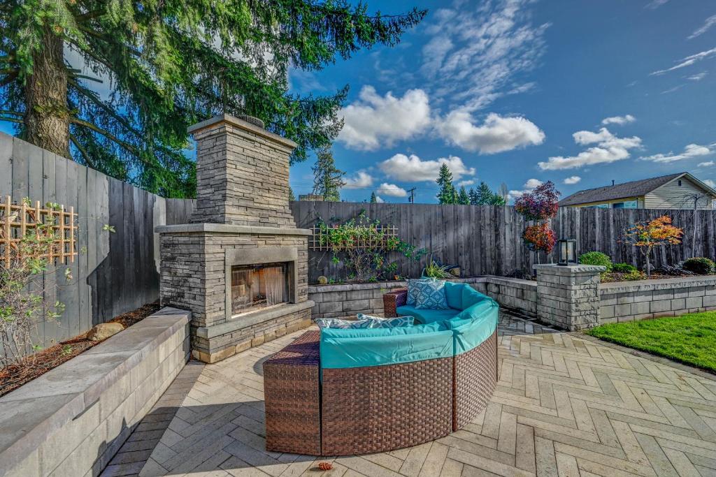a patio with a stone fireplace in a backyard at Renton Oasis- Relaxing 3BR Home with Great Outdoor! home in Renton