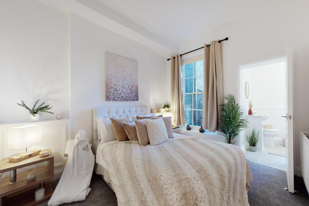 um quarto branco com uma cama e uma janela em Park Lane Apartments Baker Street em Londres