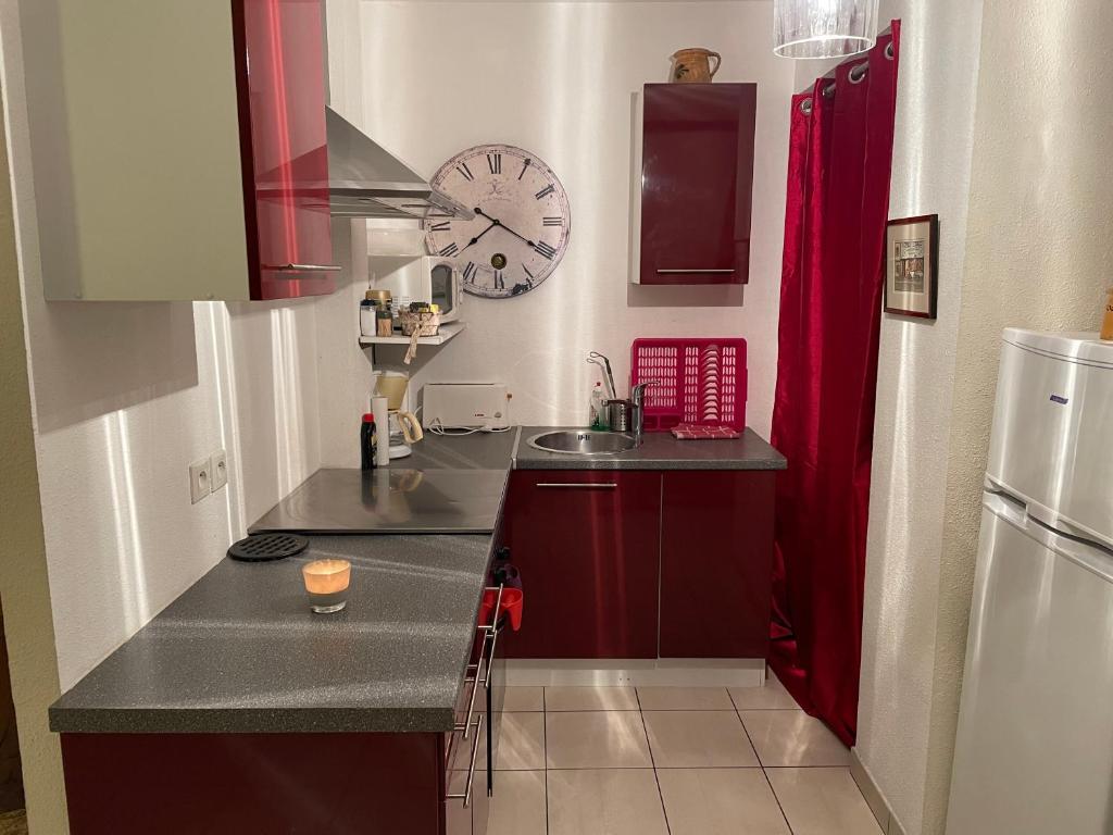 a kitchen with red cabinets and a clock on the wall at Gite de l'Oncle Hansi in Colmar