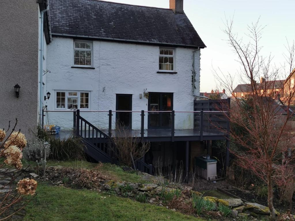 a white house with a deck in front of it at Rooms by the River at Glan Aber in Corwen