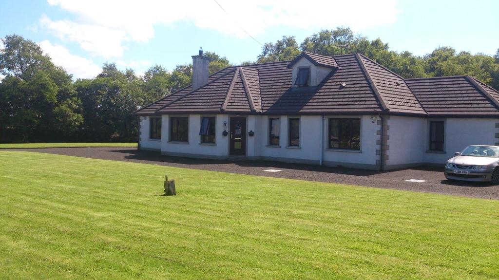 a house with a car parked in the yard at Glen Lodge in Ballymoney