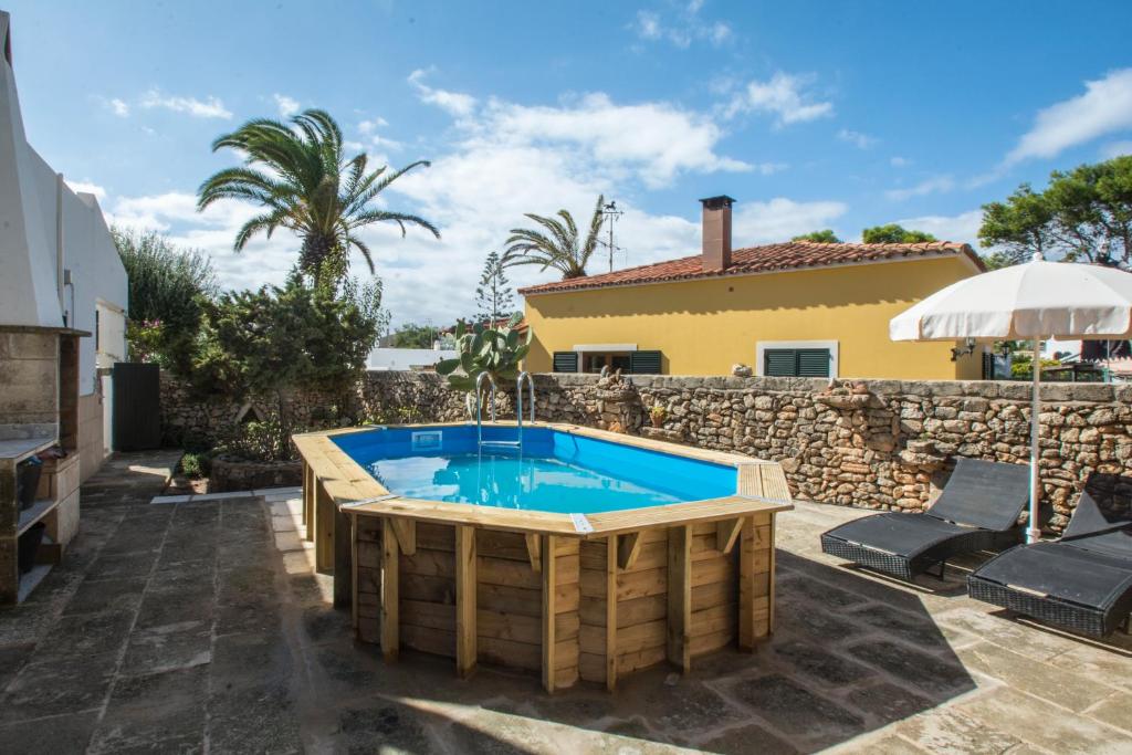 une piscine dans une arrière-cour avec un mur en pierre dans l'établissement KASSIOPEA, à Cala Blanca