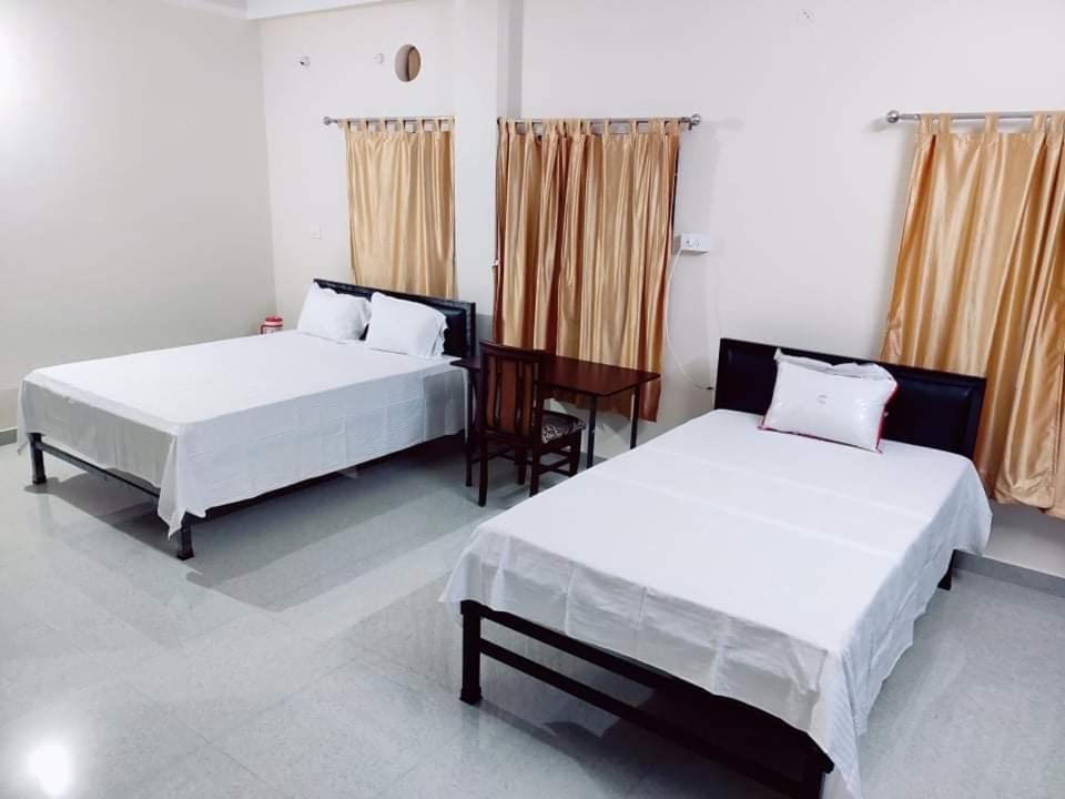 a bedroom with two beds and a desk in it at Nilachal Homes in Guwahati