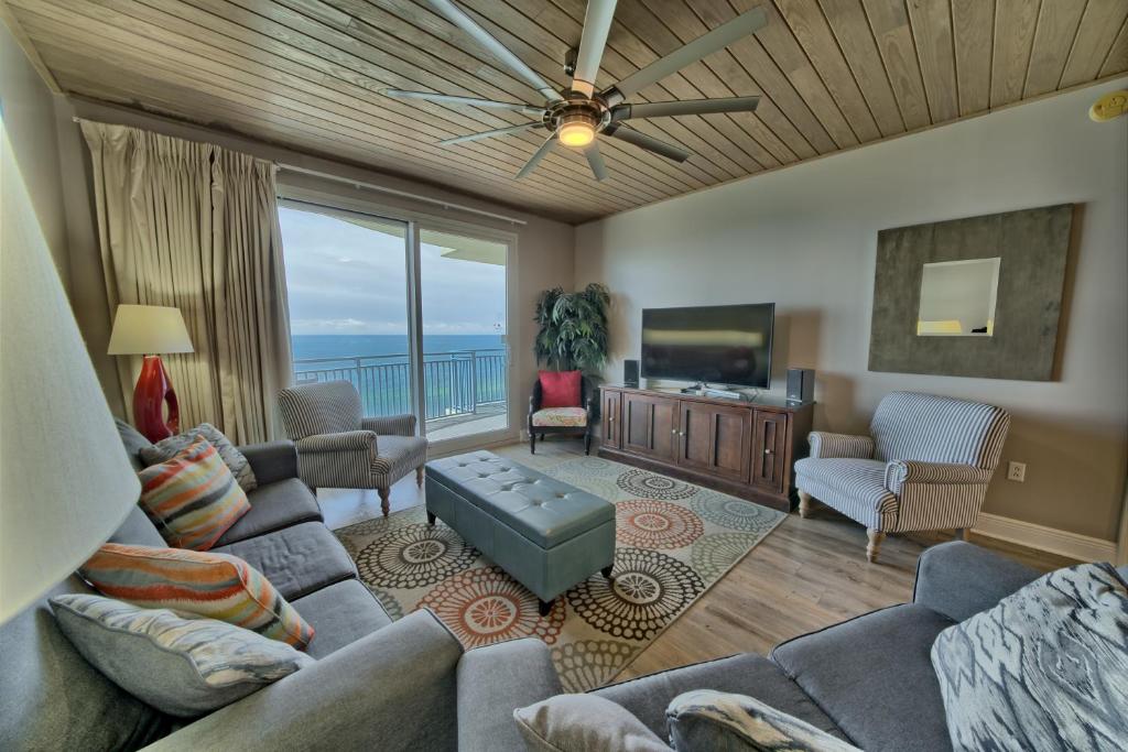 a living room with couches and a television and a balcony at Sterling Breeze - Luxury Beach Front Condo in Panama City Beach