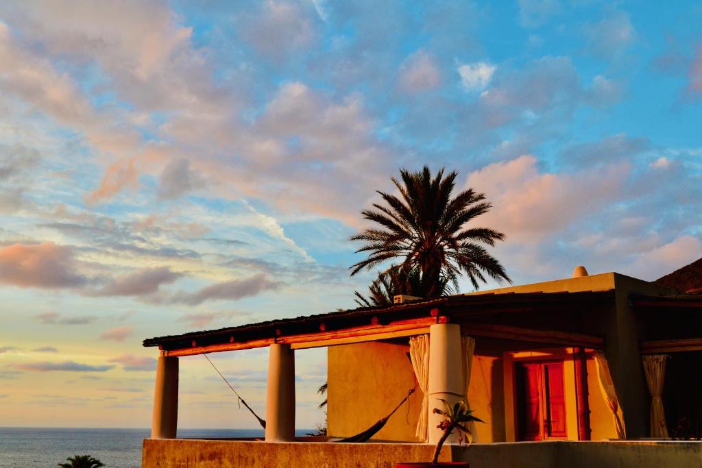 een huis met een palmboom voor de oceaan bij Hotel La Locanda Del Postino in Pollara