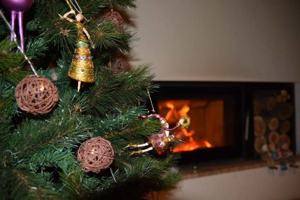 布拉索夫GreenHill Brasov的一棵挂满装饰品的圣诞树，旁边还有一个壁炉。