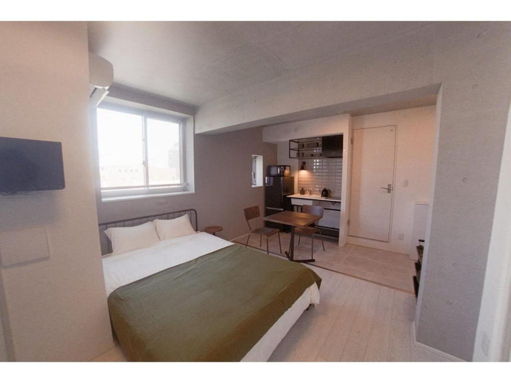 東京的住宿－AOCA Kaminoge - Vacation STAY 11982，一间卧室配有一张床、一张桌子和一个窗户。
