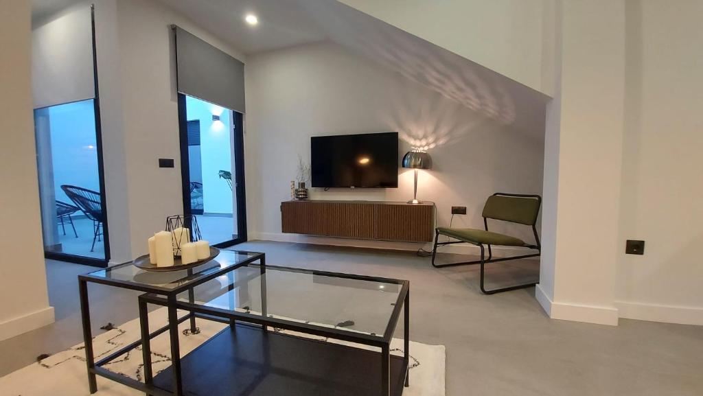 uma sala de estar com uma televisão e uma mesa de vidro em Apartamento Golddem Mercedes. em Málaga