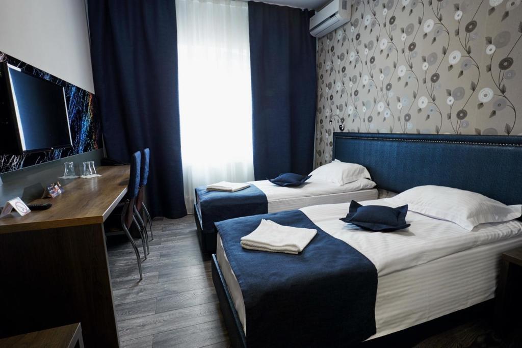 um quarto de hotel com duas camas, uma secretária e uma mesa em Vila Iris em Chisinau