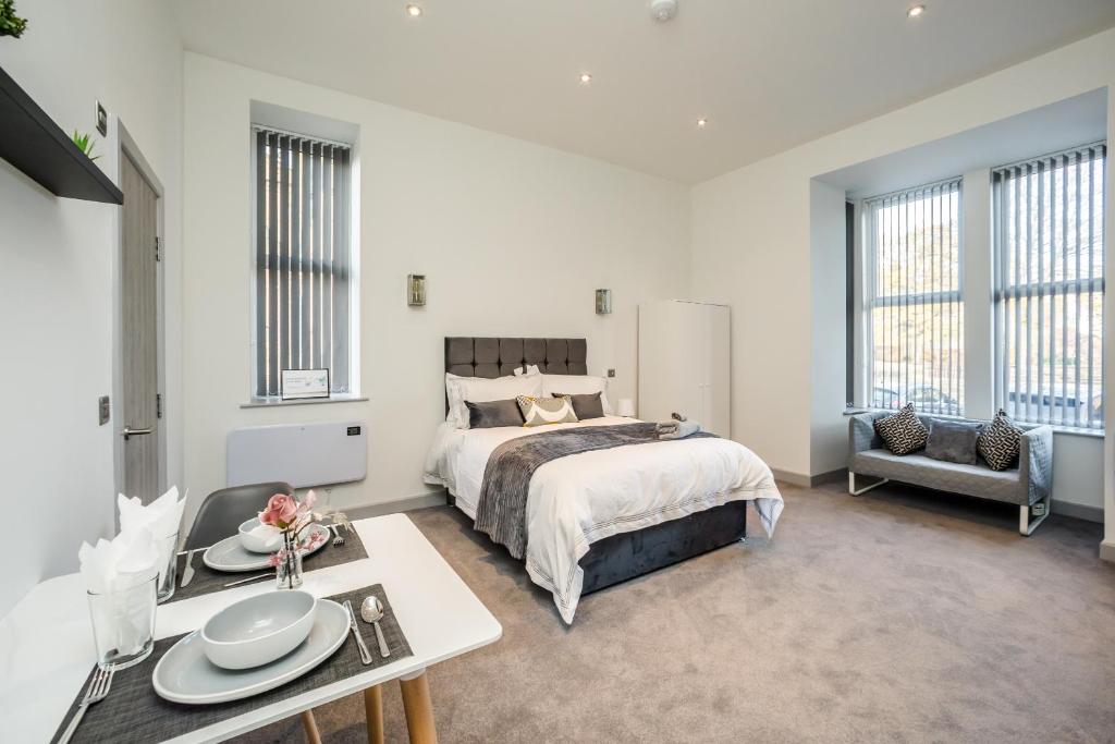 a bedroom with a bed and a table with plates on it at Exquisite Serviced Studio @ Greenhead Central in Huddersfield
