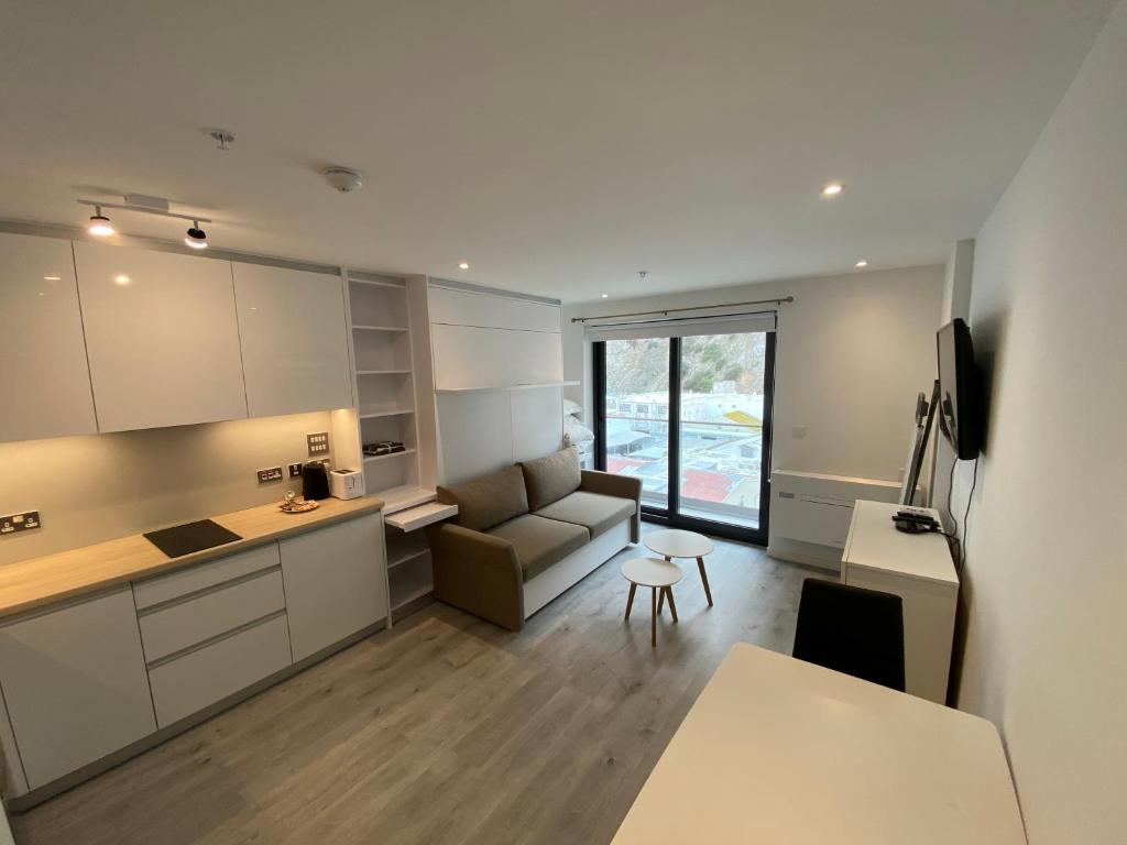 直布羅陀的住宿－Modern Studio Apartment at The Hub，厨房以及带沙发和桌子的客厅。